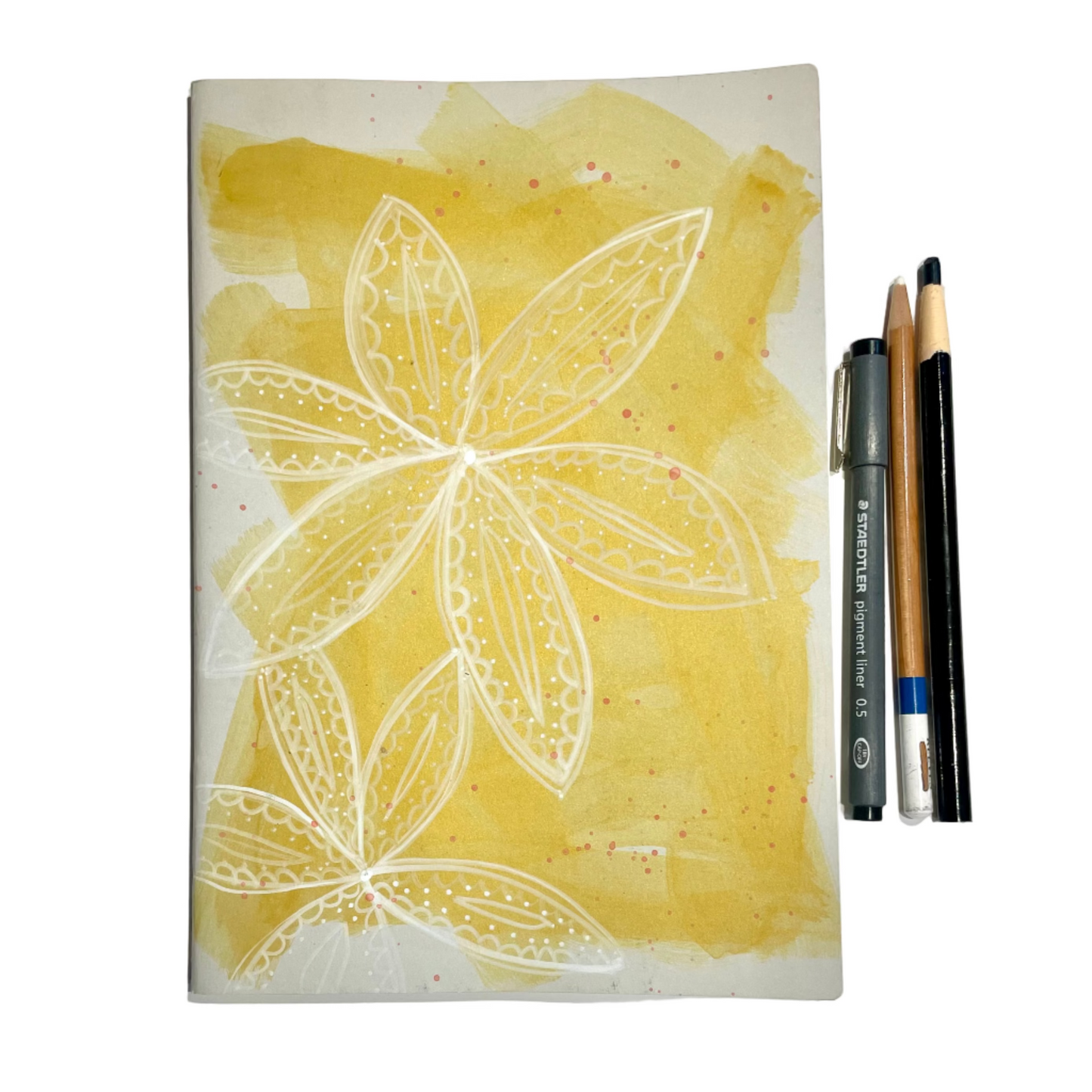 Notebook with floral design on a yellow background, accompanied by drawing tools.