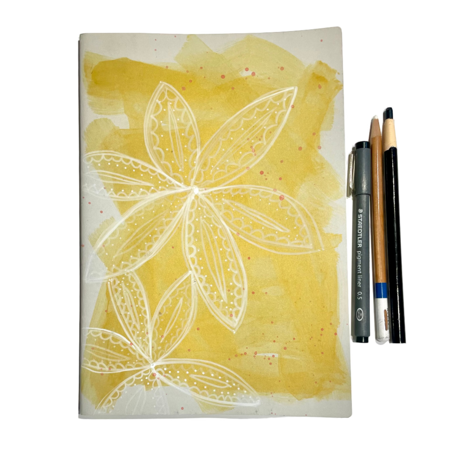 Notebook with floral design on a yellow background, accompanied by drawing tools.