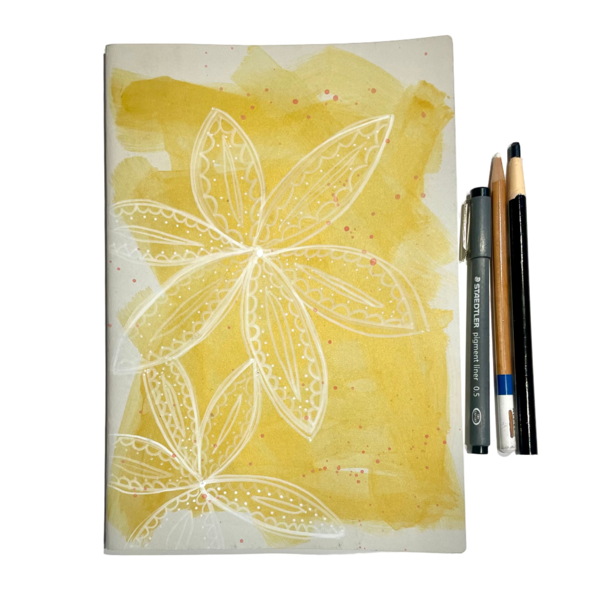 Notebook with floral design on a yellow background, accompanied by drawing tools.