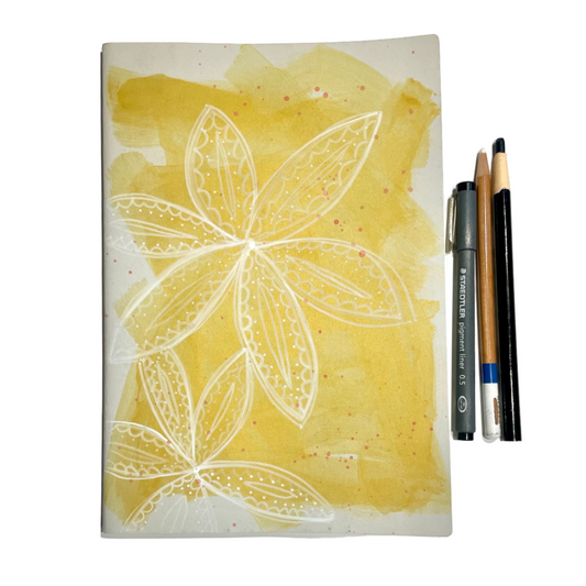 Notebook with floral design on a yellow background, accompanied by drawing tools.